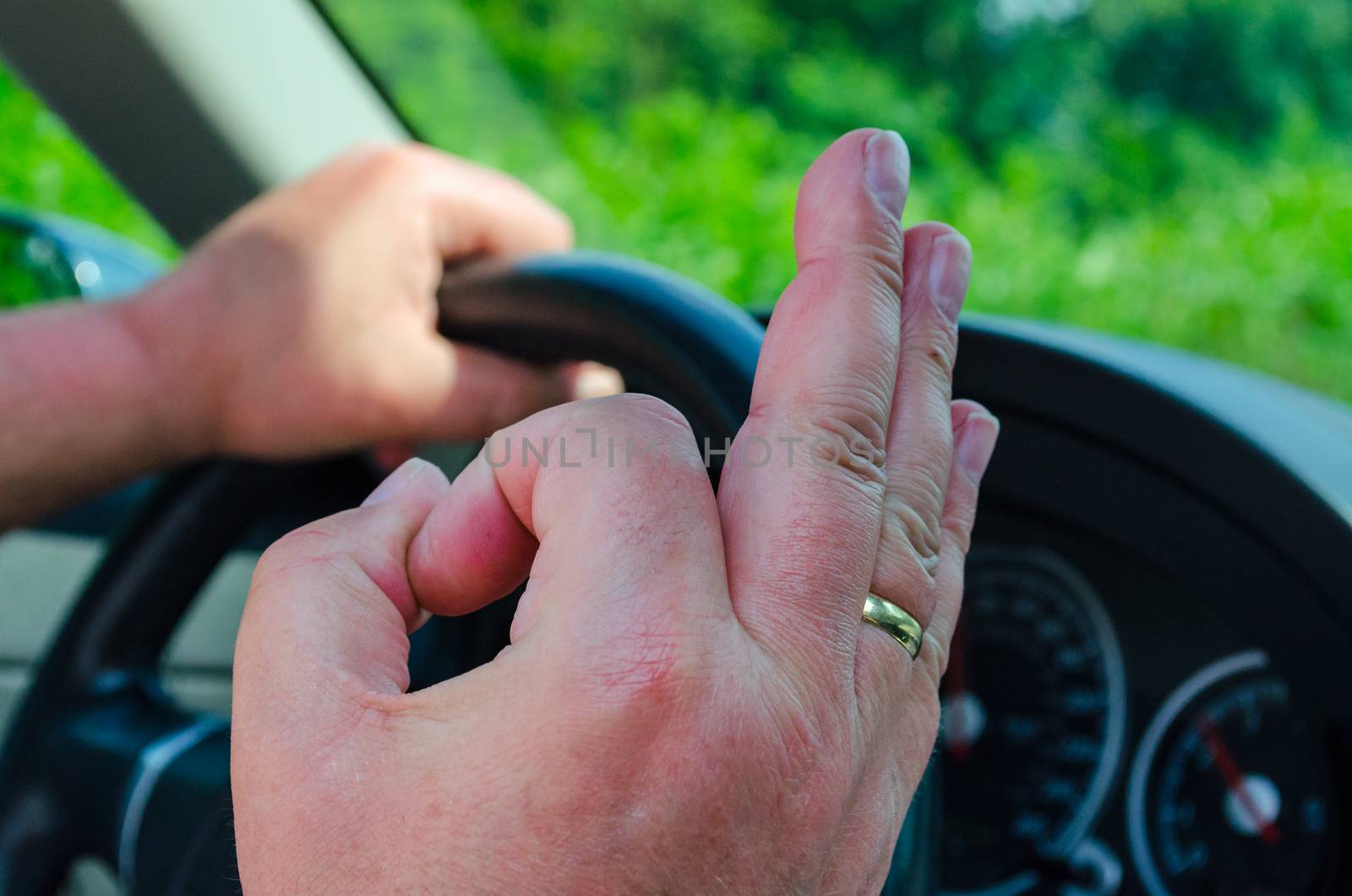 Hand on the wheel, the other hand shows the OK sign.