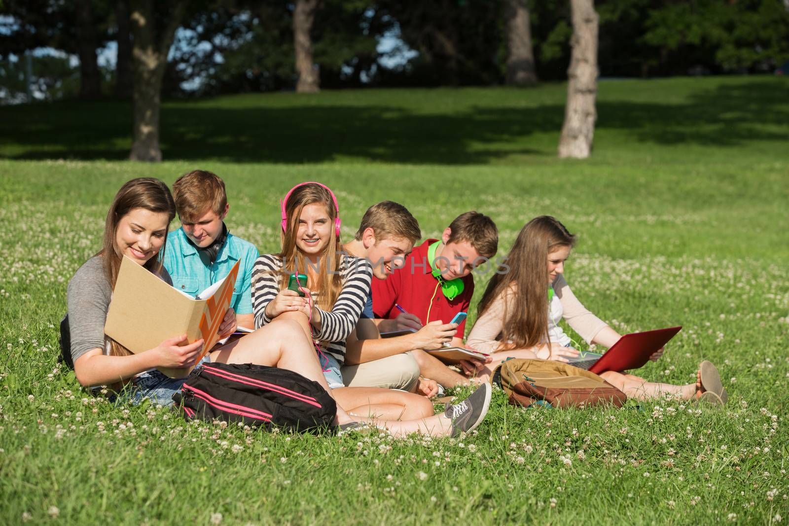 Cute group of students with books and laptop working outdoors
