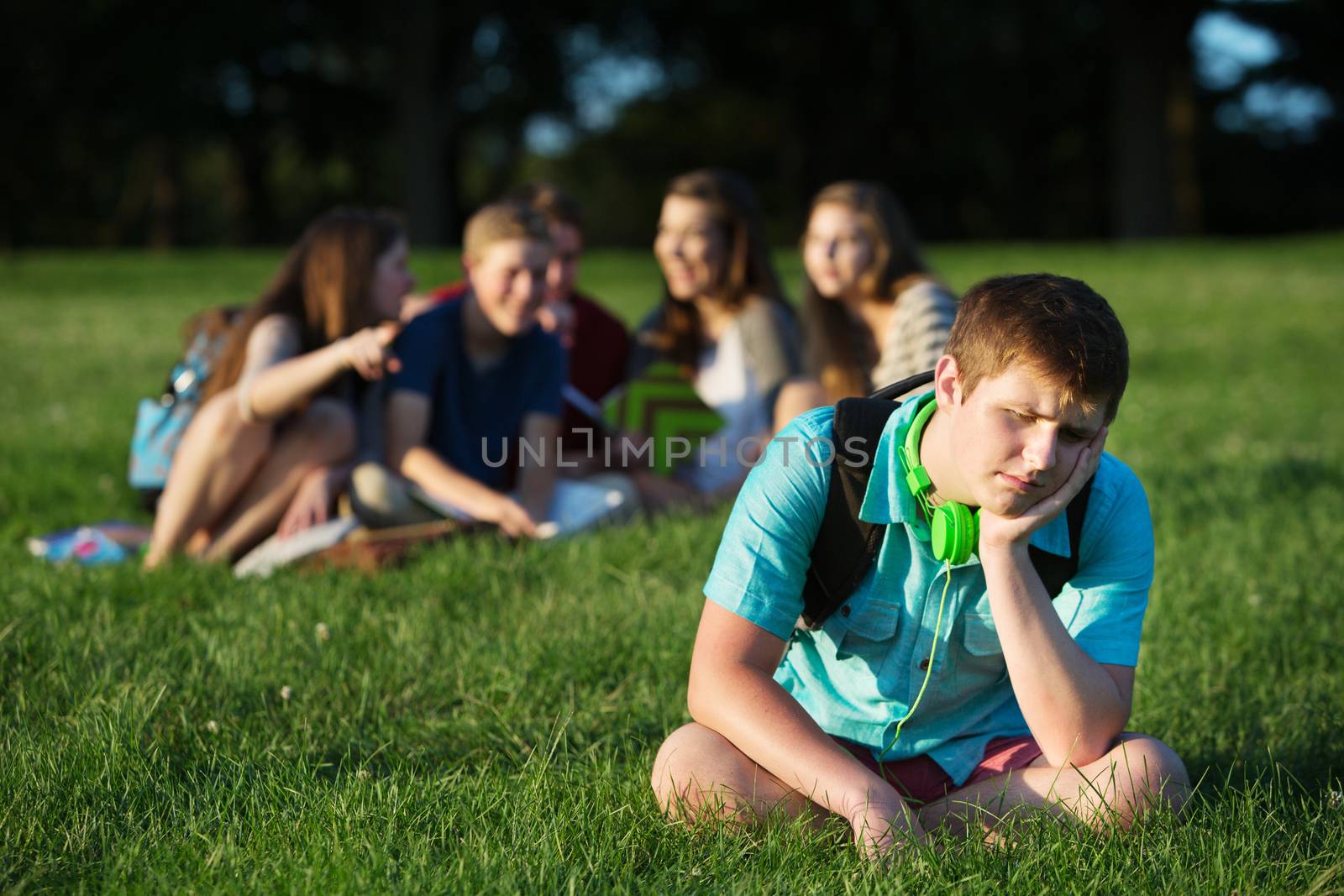 Group of teen bullying sad student sitting outdoors