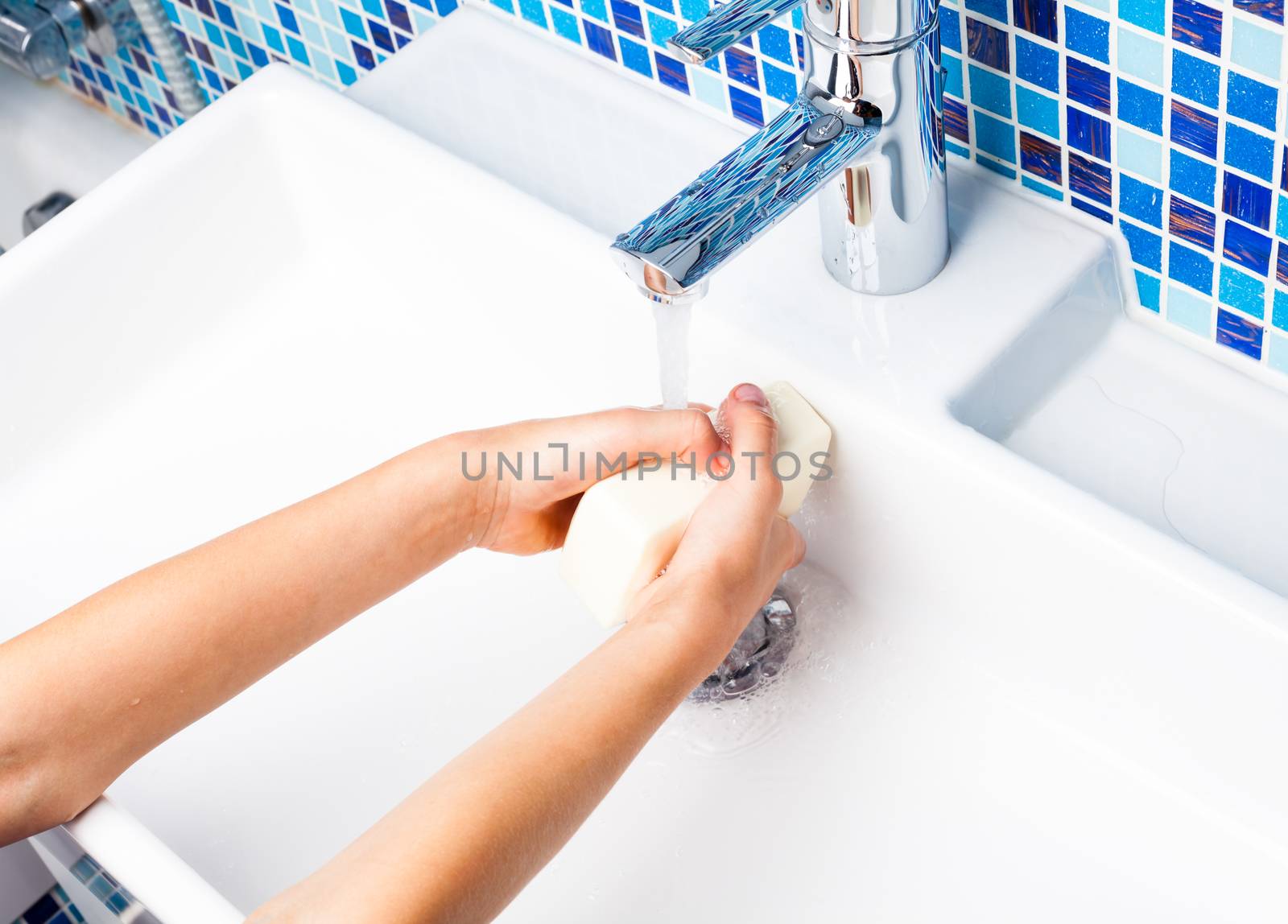 Girl washing her hands with soap in a bathroom sink