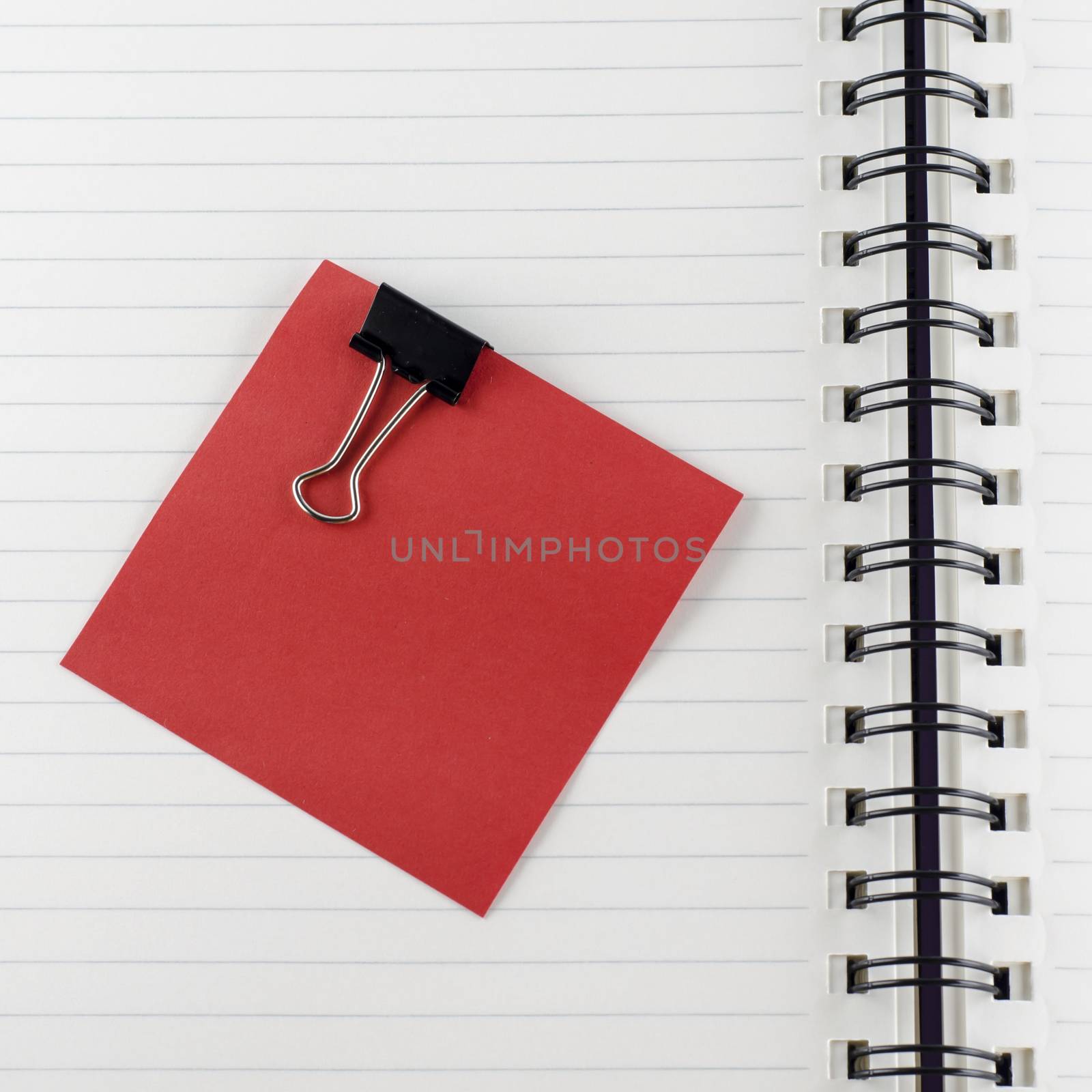 red paper note with black clip on notebook