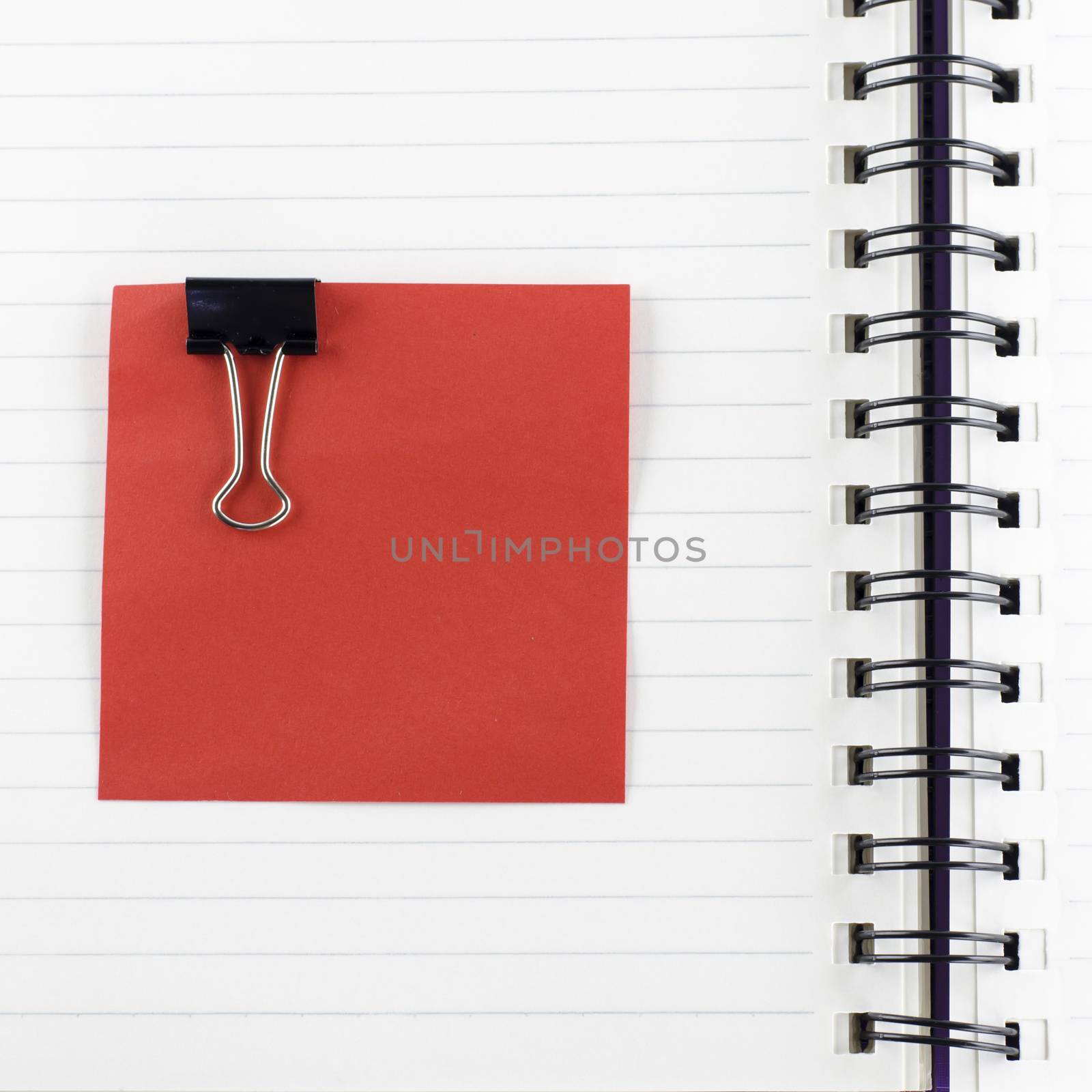 red paper note with black clip on notebook