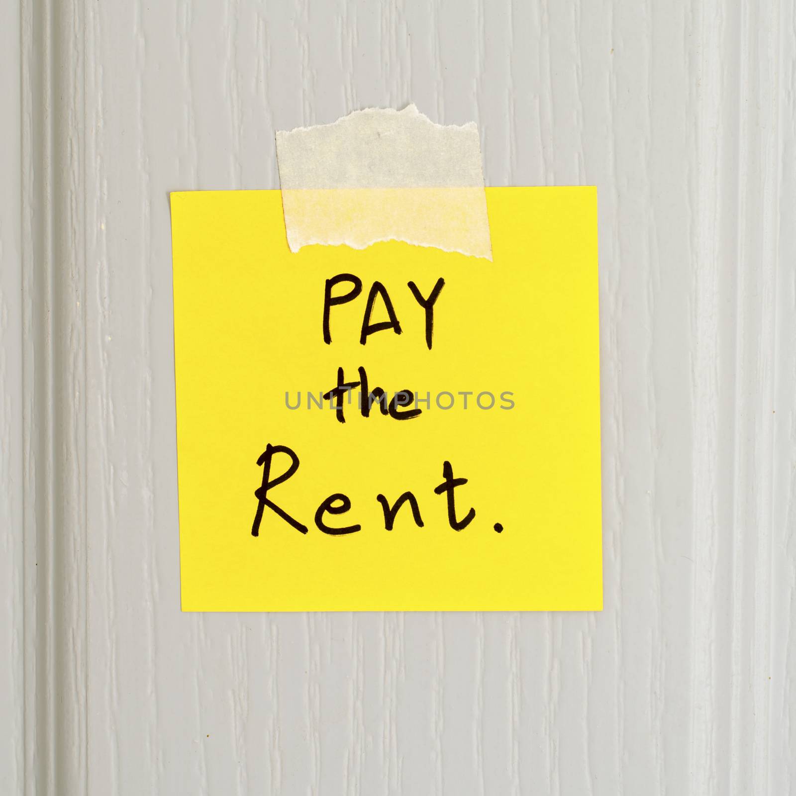 sticky note write a message pay the rent on wood door background