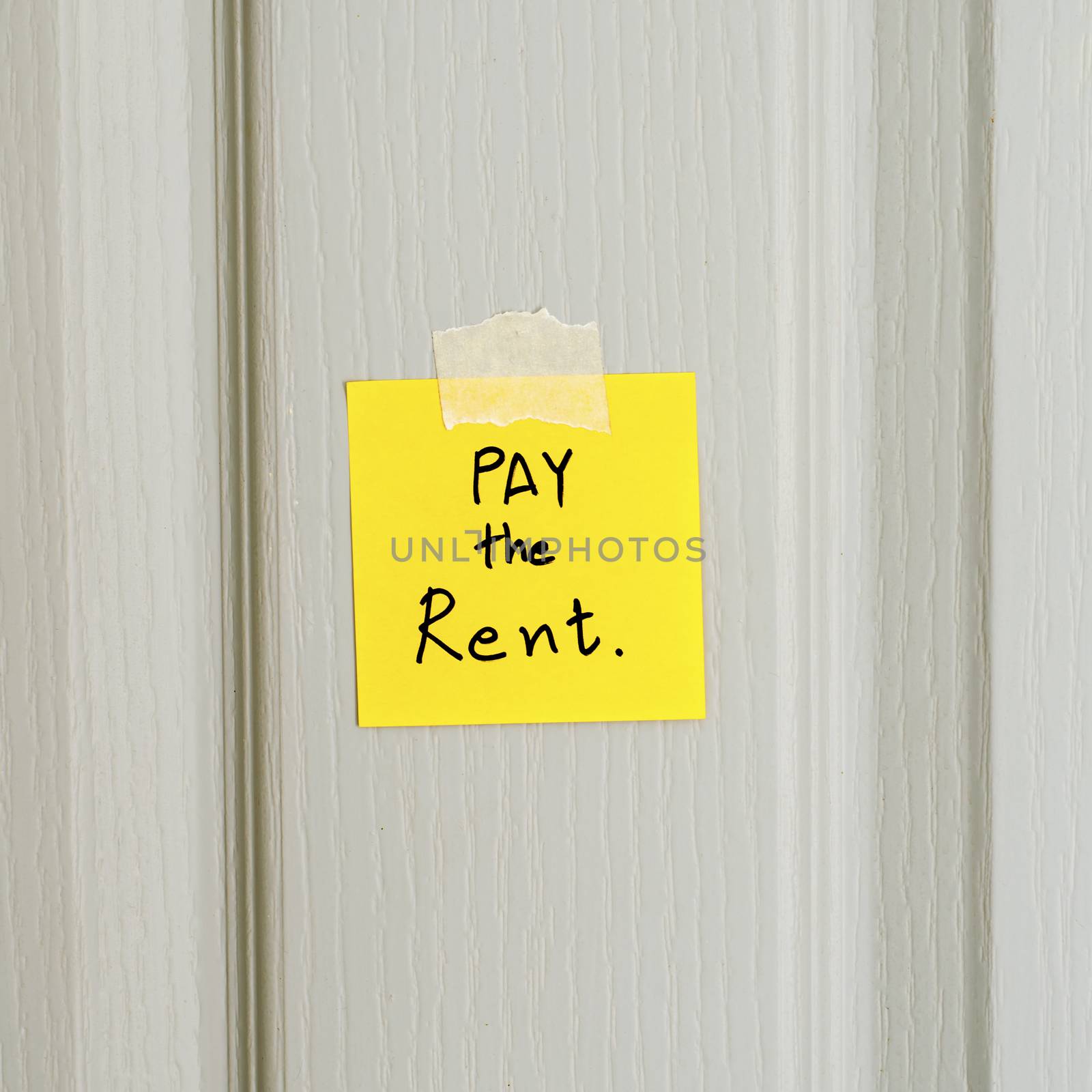sticky note write a message pay the rent on wood door background