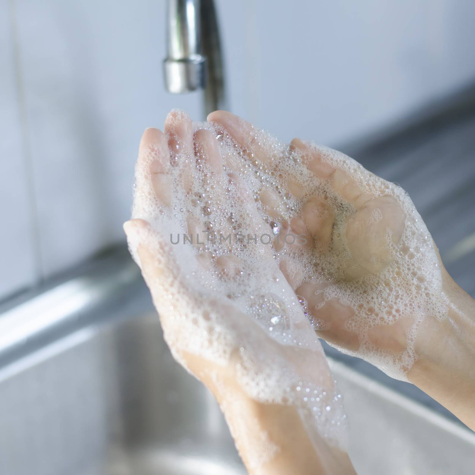 Washing of hands with soap on sink