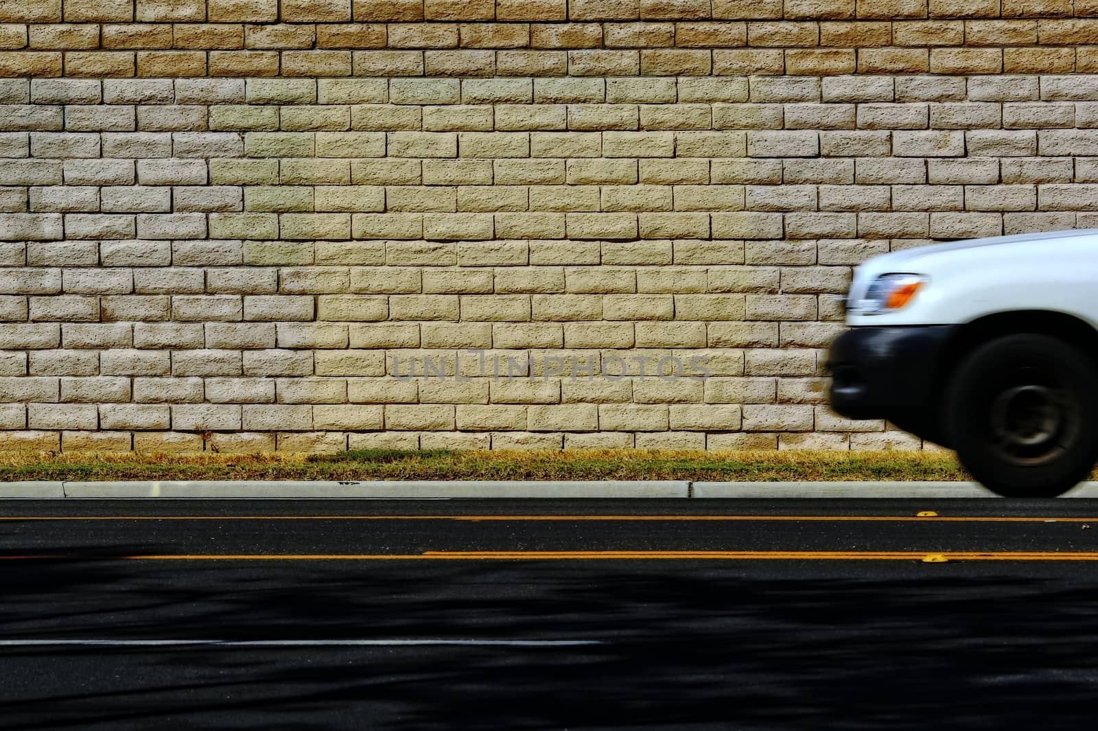 White car on the road with brick wall background.