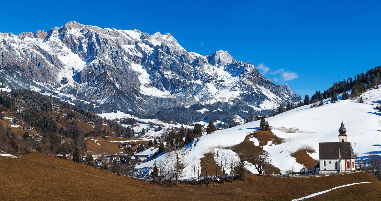 Beautiful winter Austrian panorama with mountains and church.