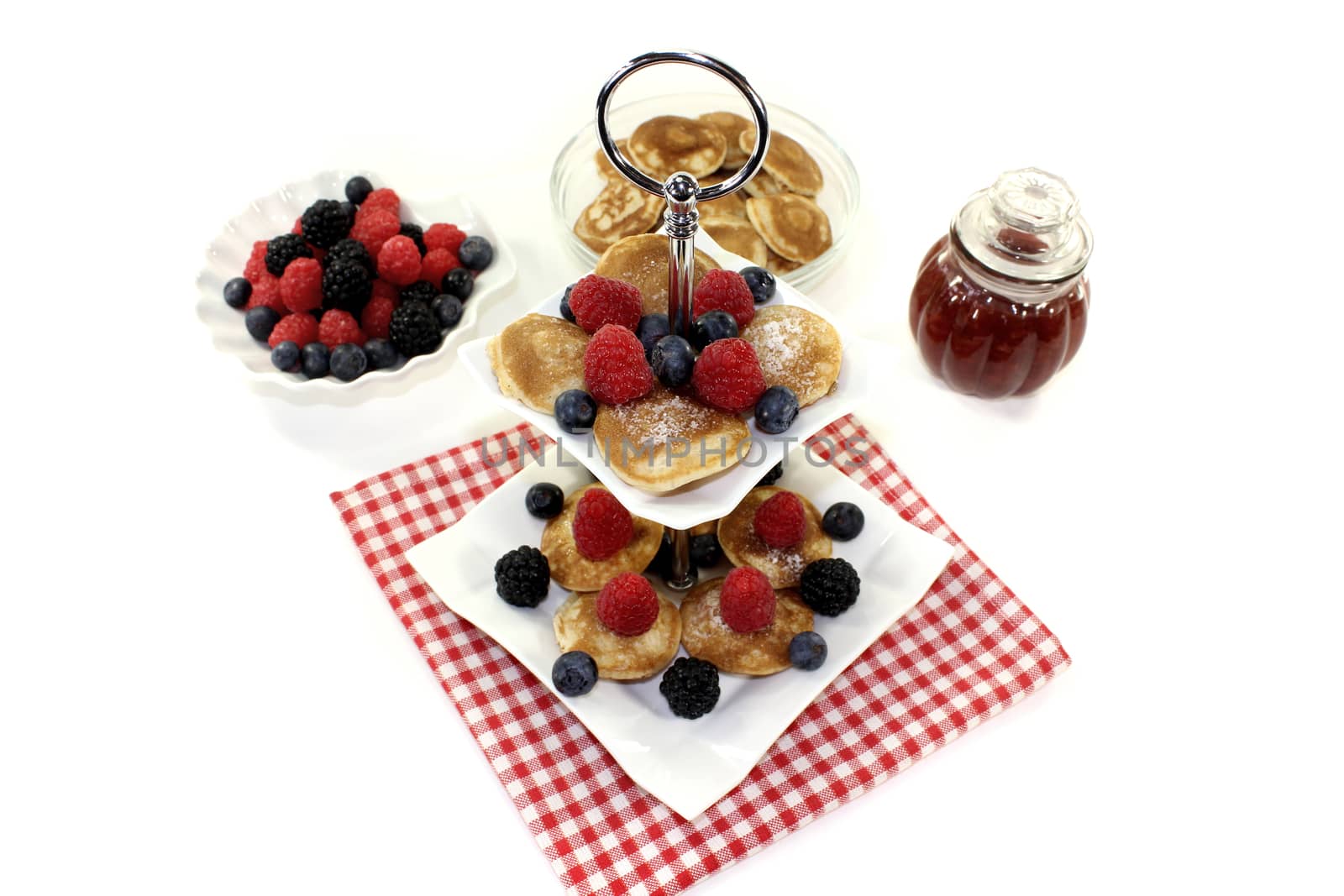 Poffertjes with raspberries on a cake stand on a light background