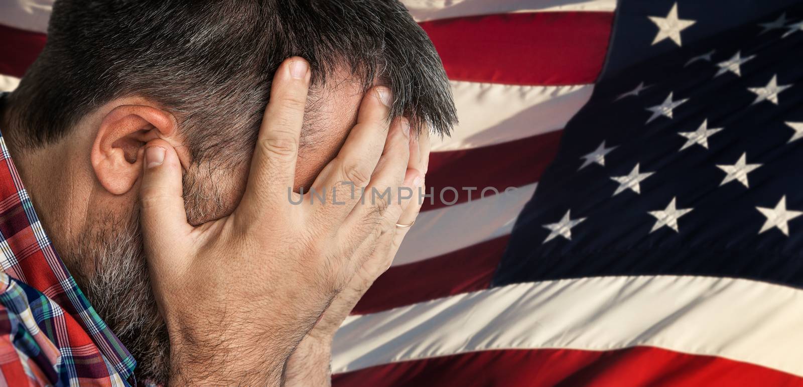 Veteran. Portrait of an elderly man with face closed by hand on USA flag background. 