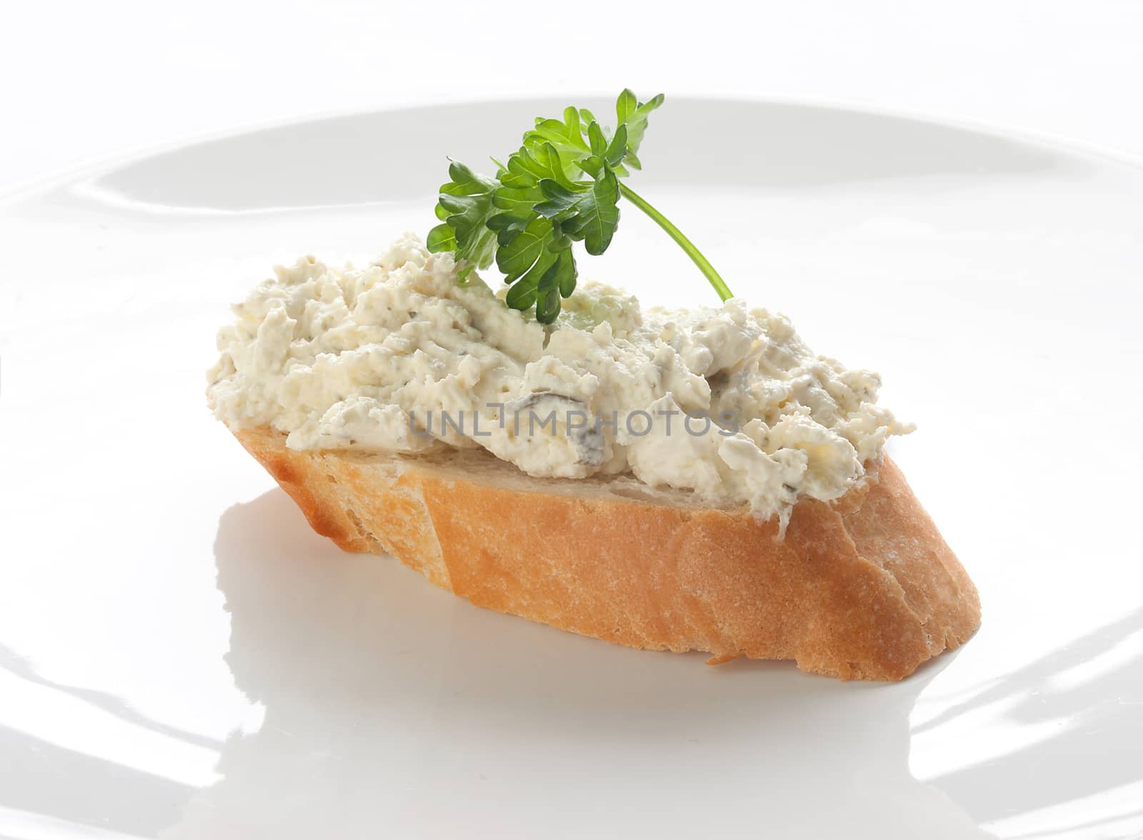 Sandwich with long loaf, cottage cheese and parsley on the white plate;