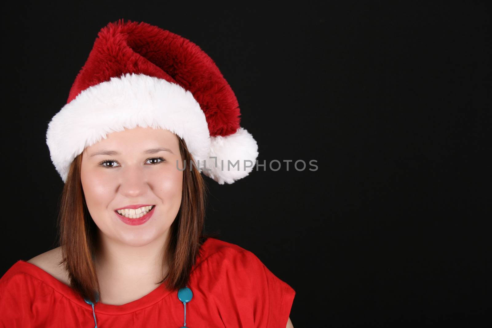 Cheerful young brunette wearing a red top and christmas hat 