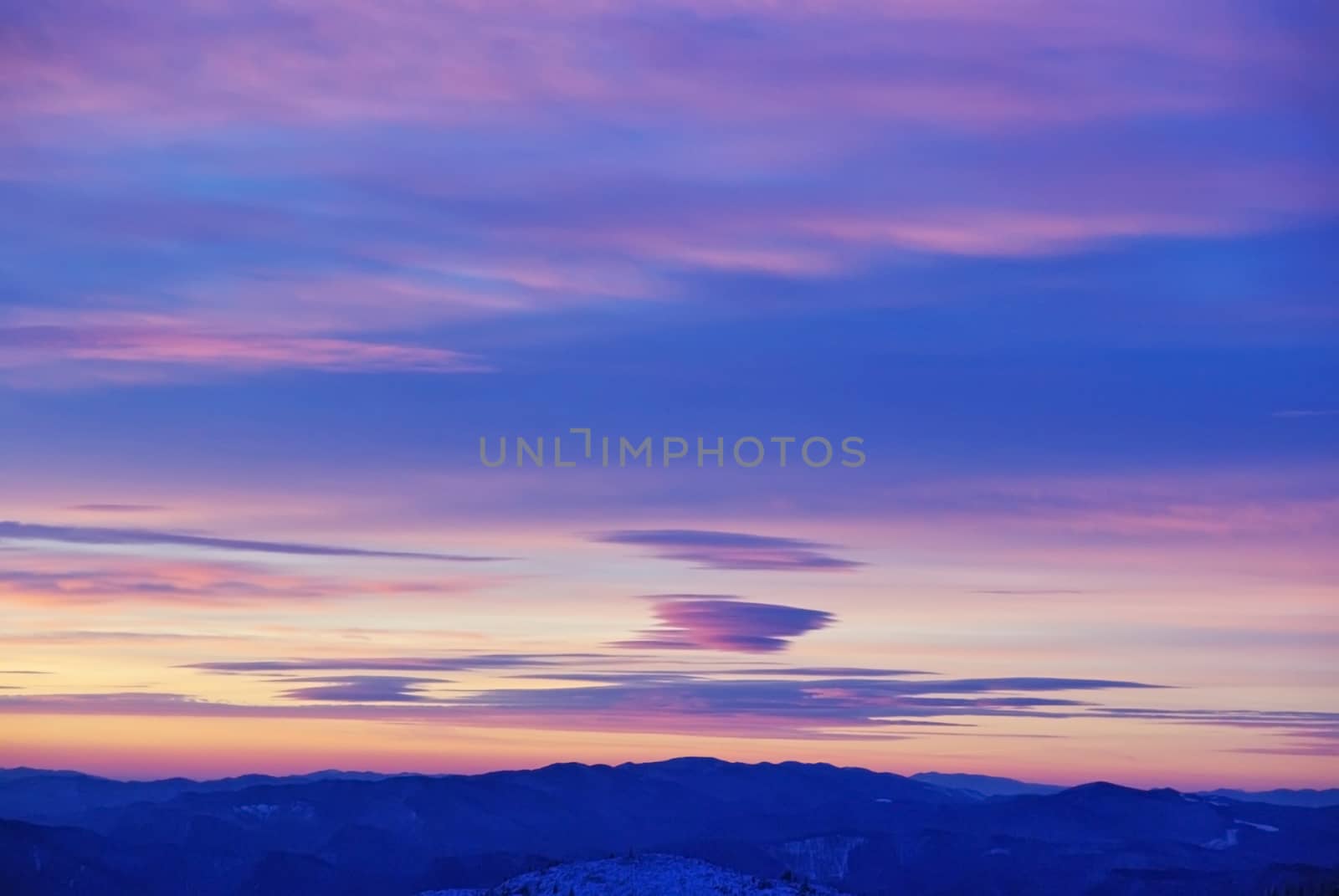 Colored clouds at sunrise over the mountains.