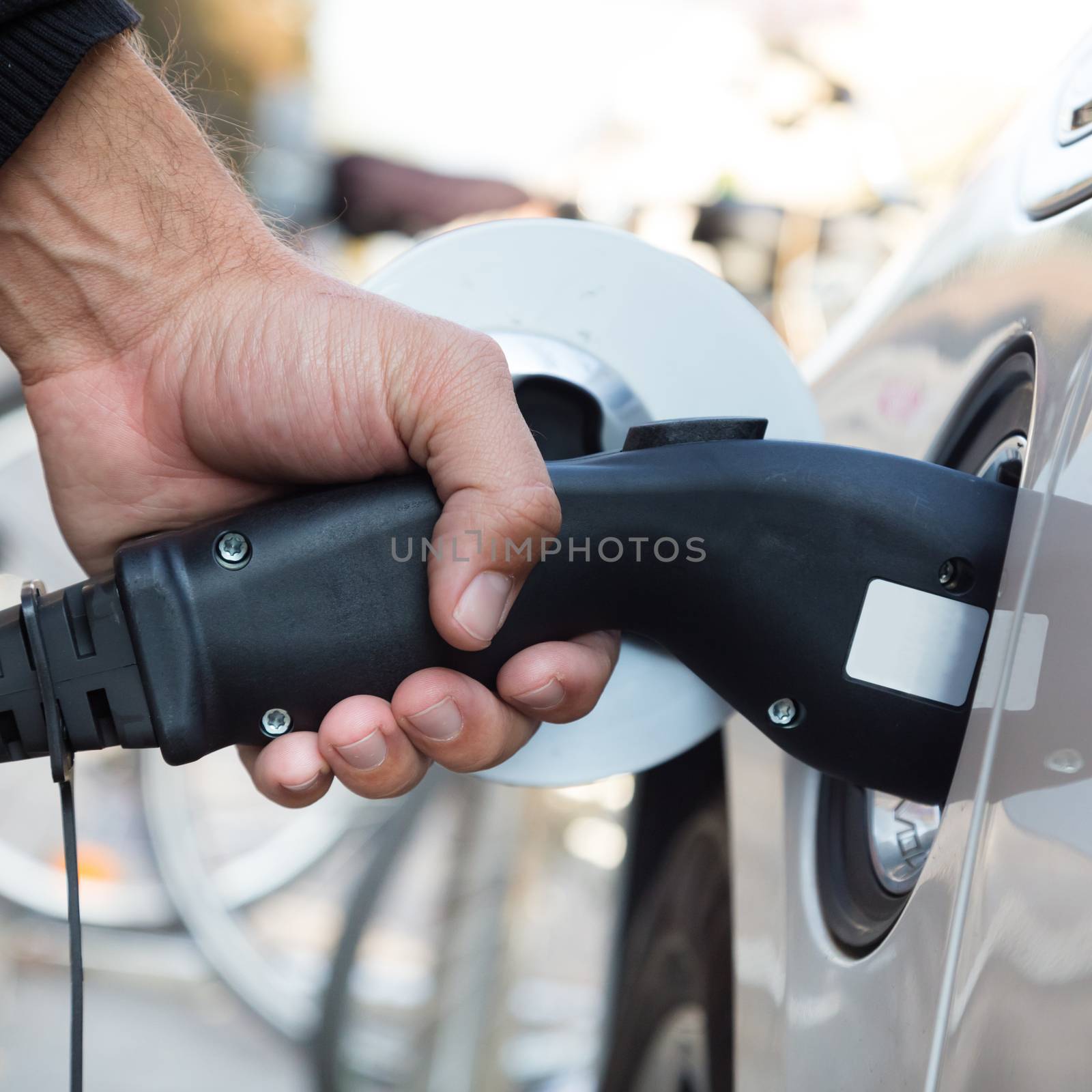 Power supply for electric car charging.  Electric car charging station. Close up of the power supply plugged into an electric car being charged.