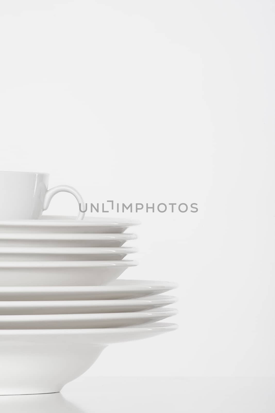 studio shot of a pile of white plates and white cup isolated on white