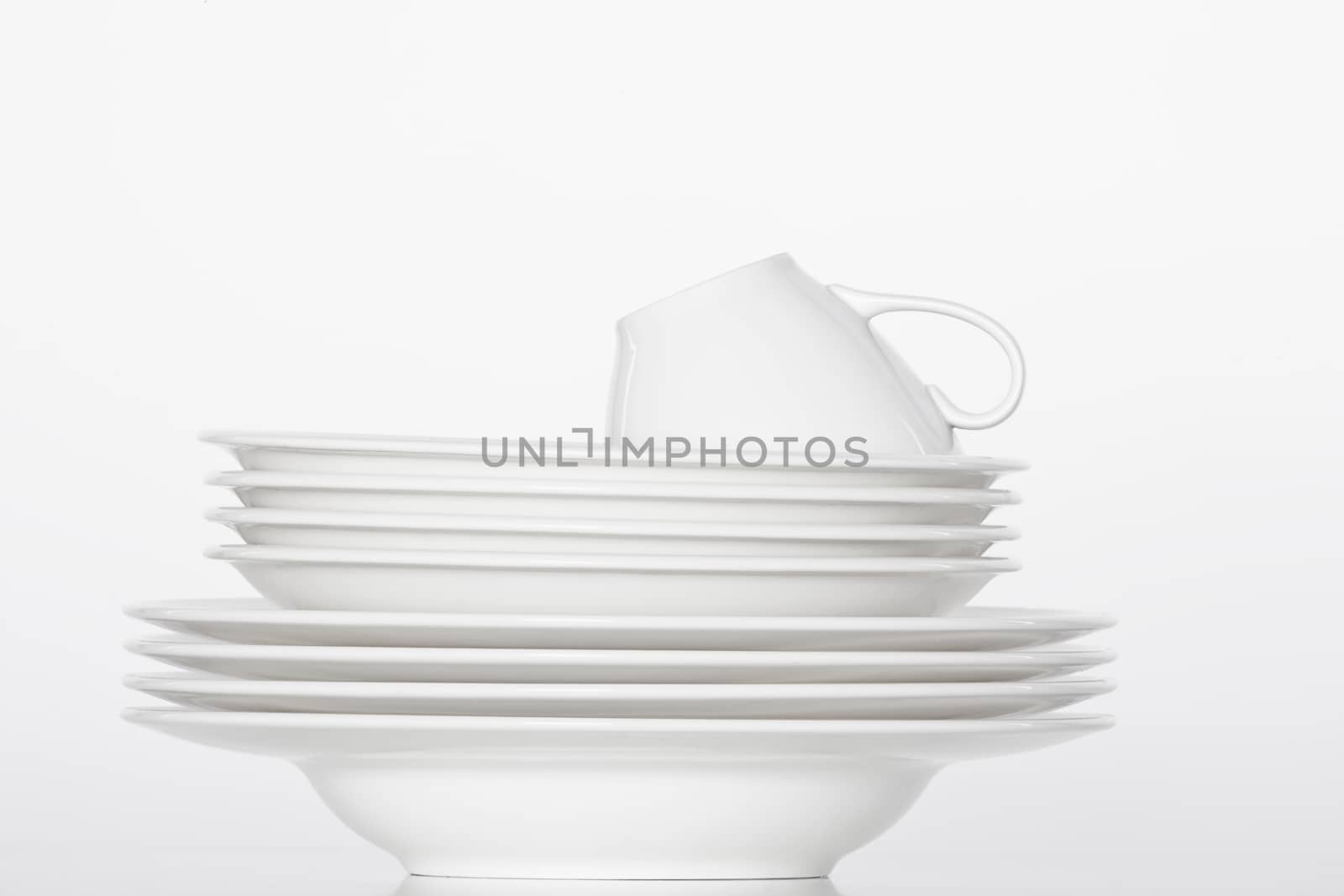 studio shot of a pile of white plates and white cup isolated on white