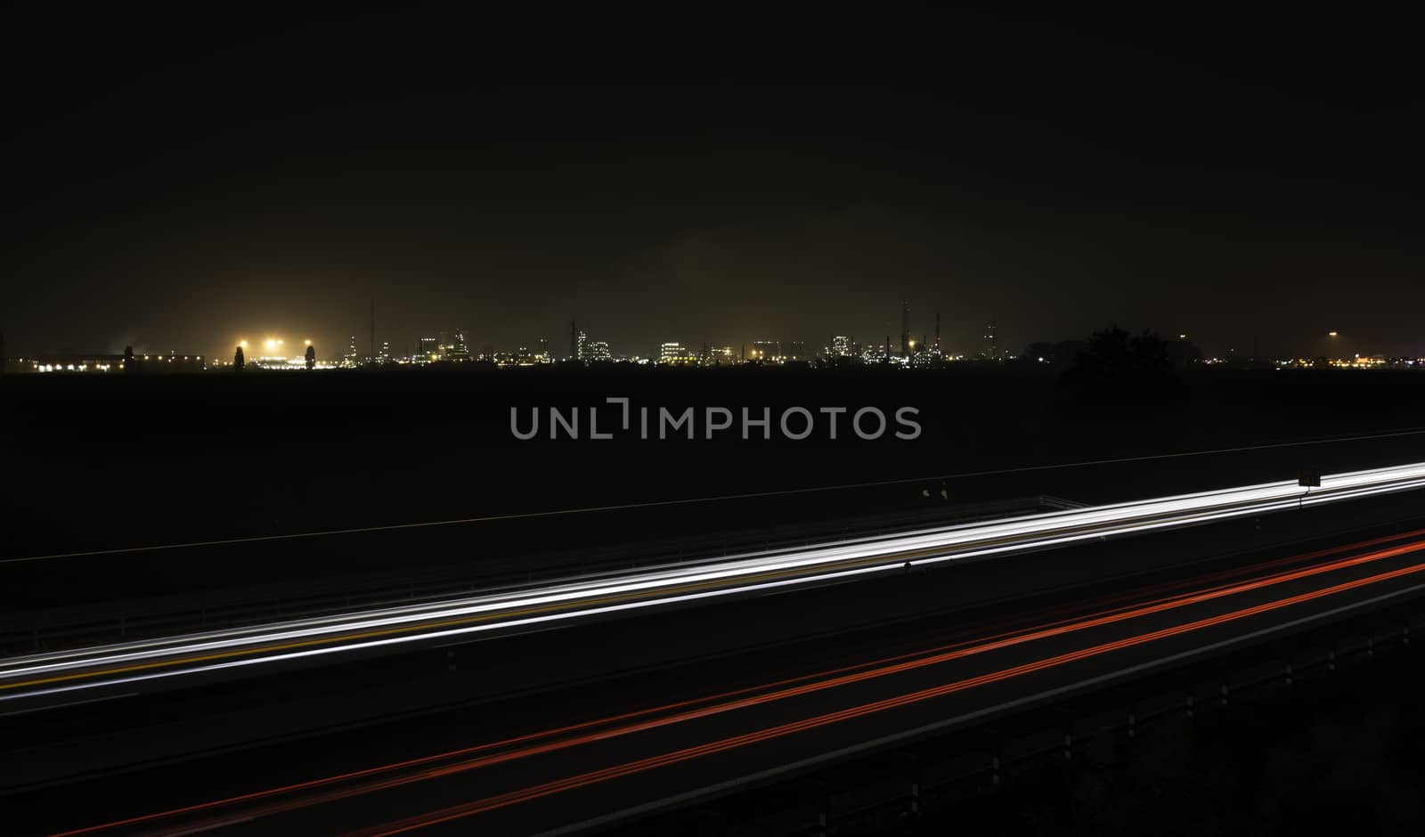 Car trails with an industrial plant on the background