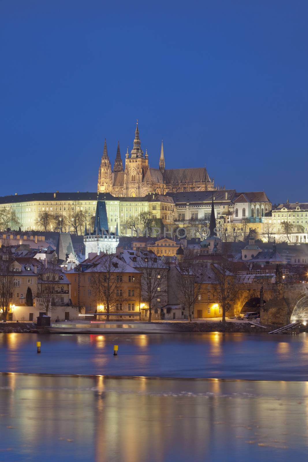 prague in winter - charles bridge and hradcany castle at dusk