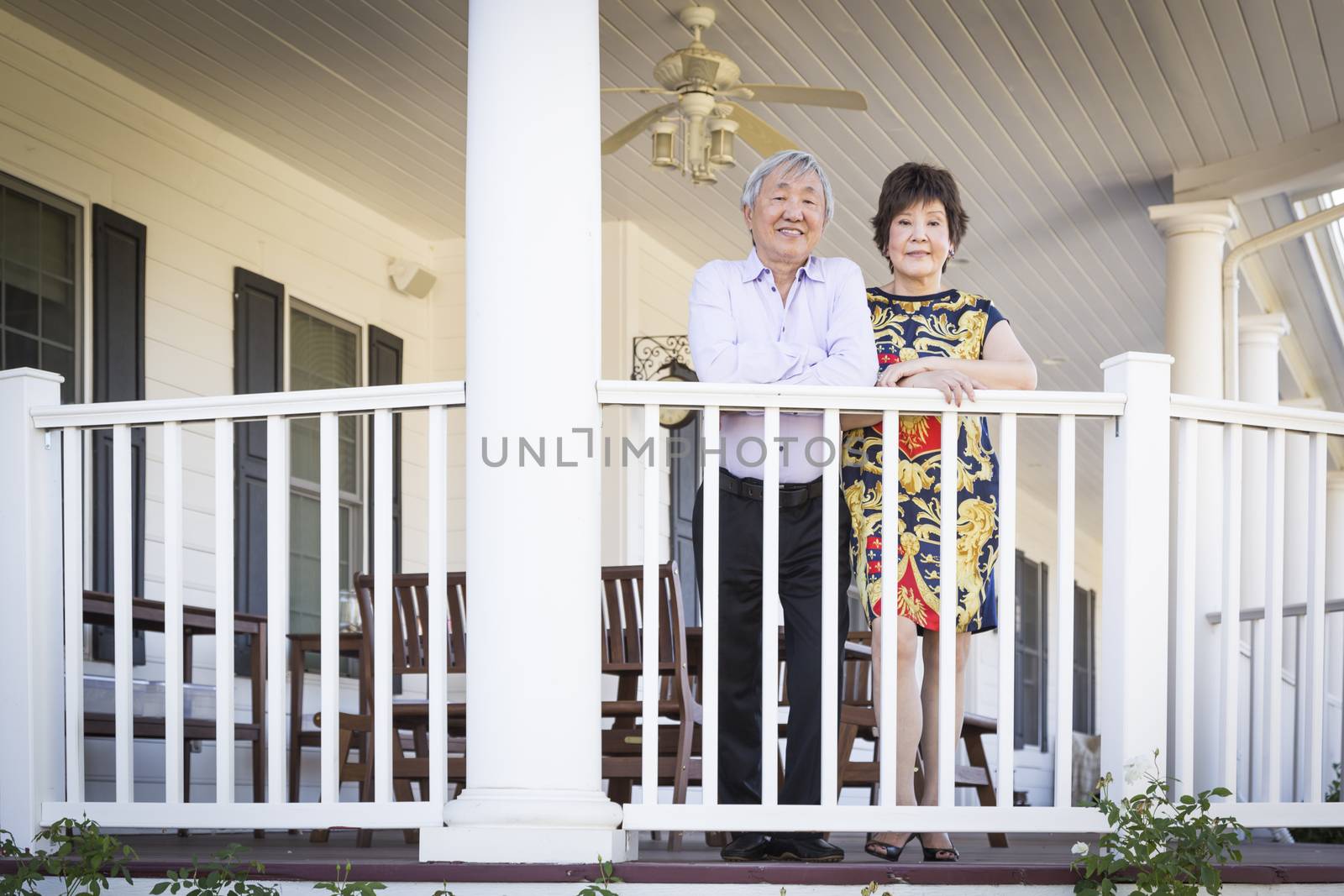 Attractive Happy Chinese Couple Enjoying Their House Outside.