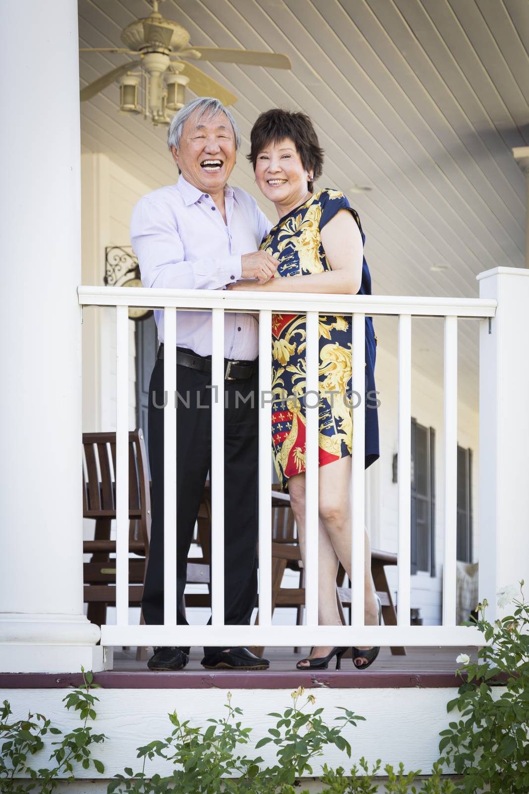 Attractive Happy Chinese Couple Enjoying Their House Outside.