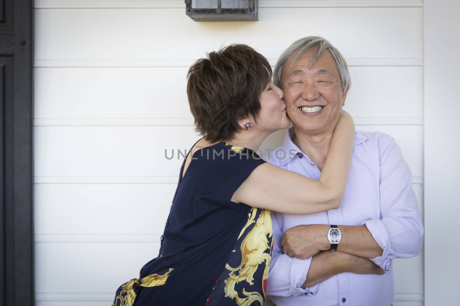 Attractive Happy Chinese Couple Enjoying Their House Outside.