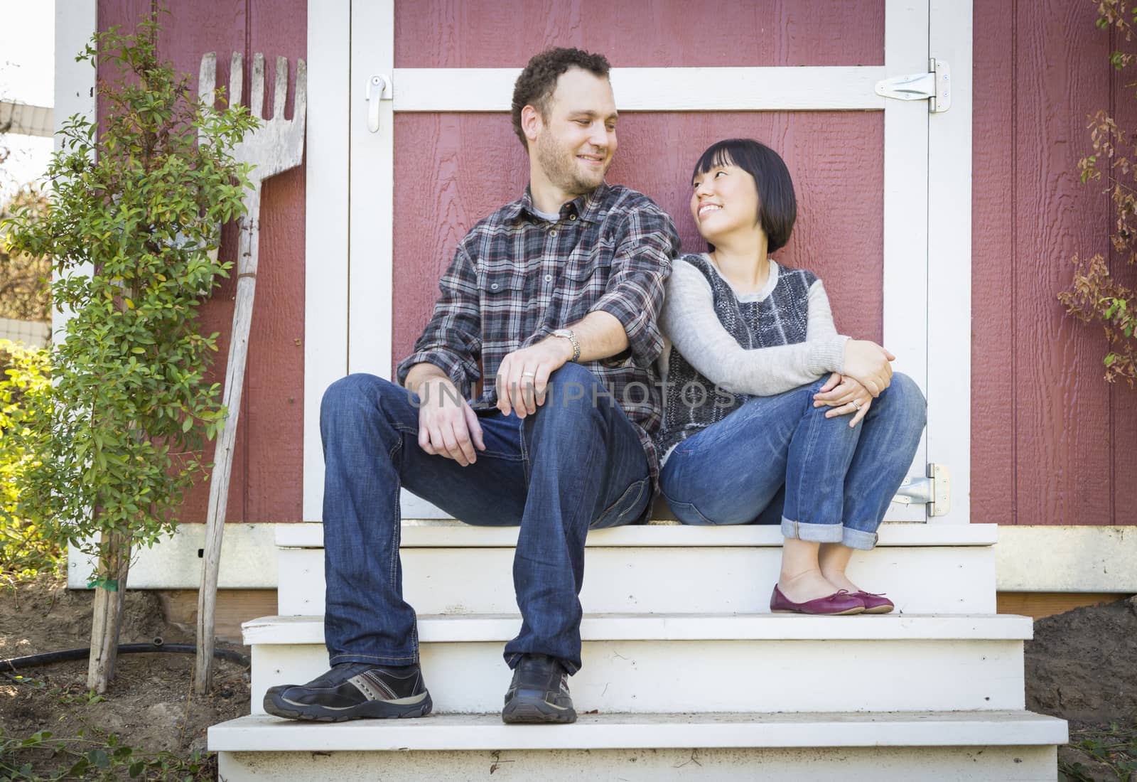 Happy Mixed Race Couple Relaxing on the Steps of Their Barn.