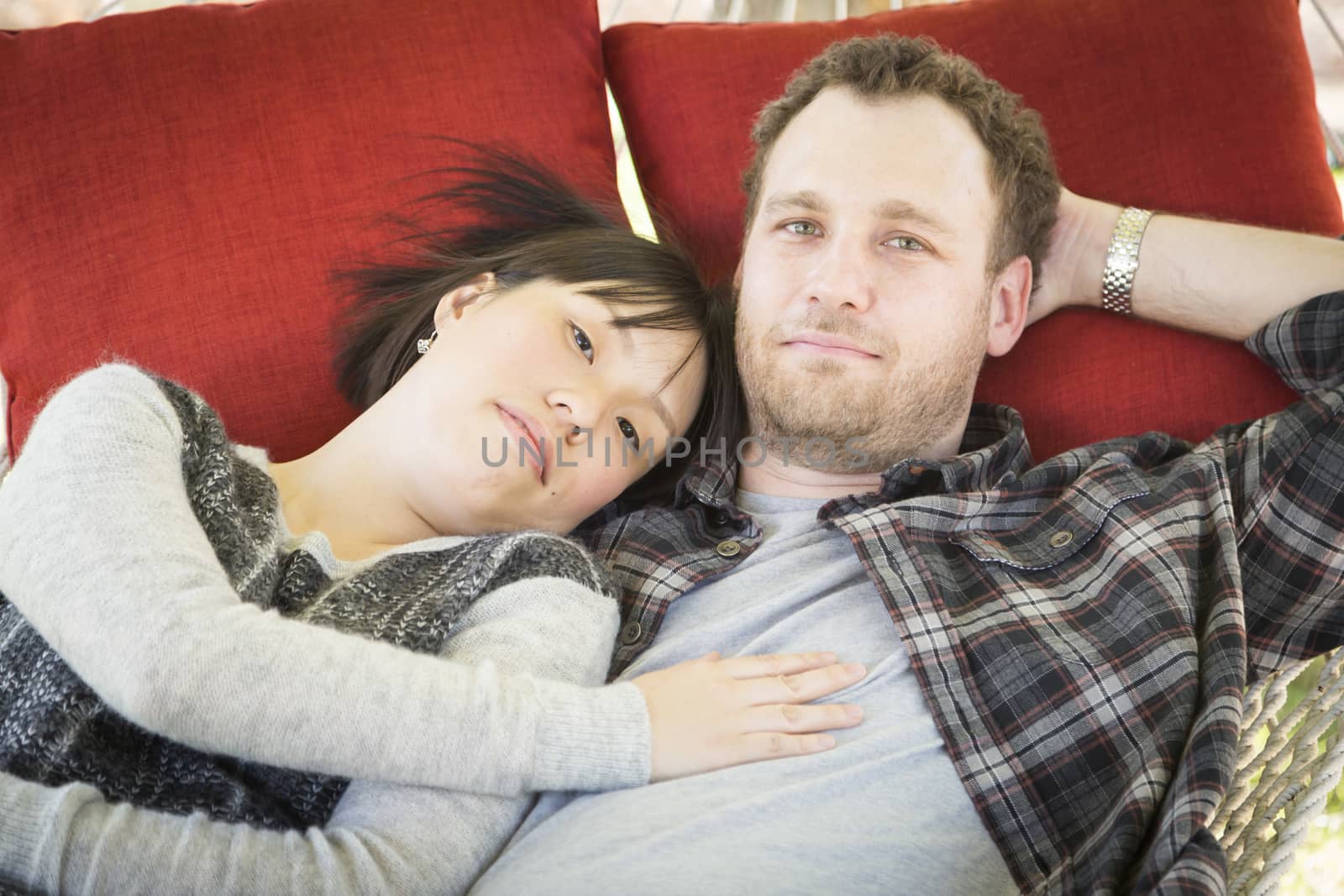 Happy Mixed Race Couple Relaxing in a Hammock Outside.