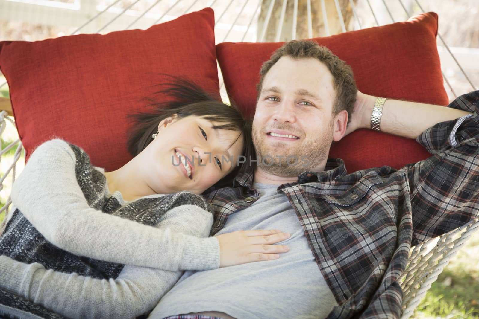 Happy Mixed Race Couple Relaxing in a Hammock Outside.