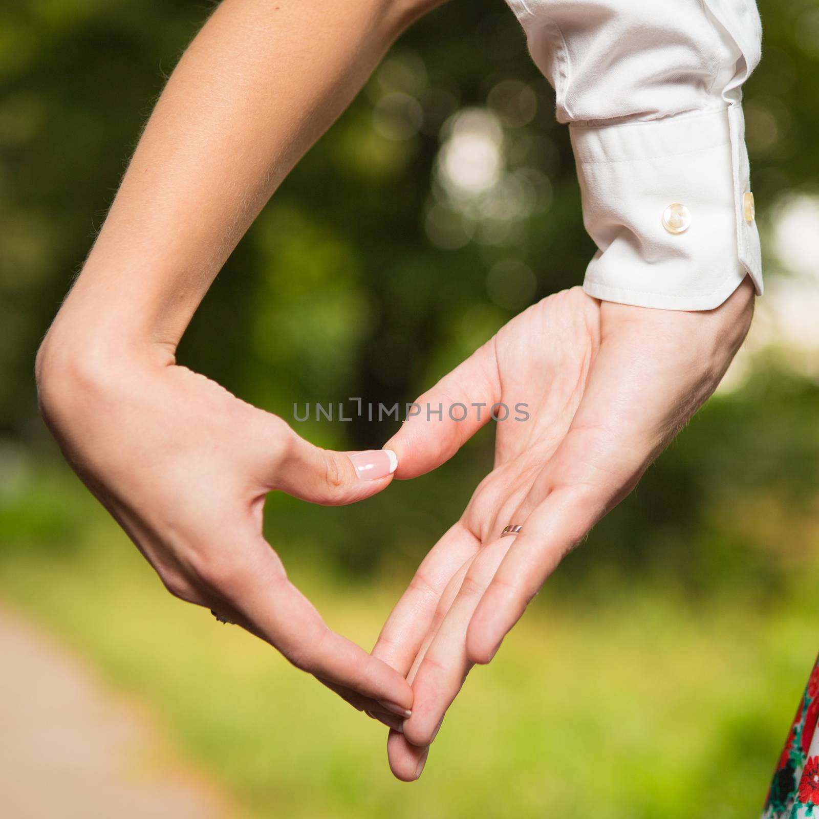 Bride and groom standing together with heart in park