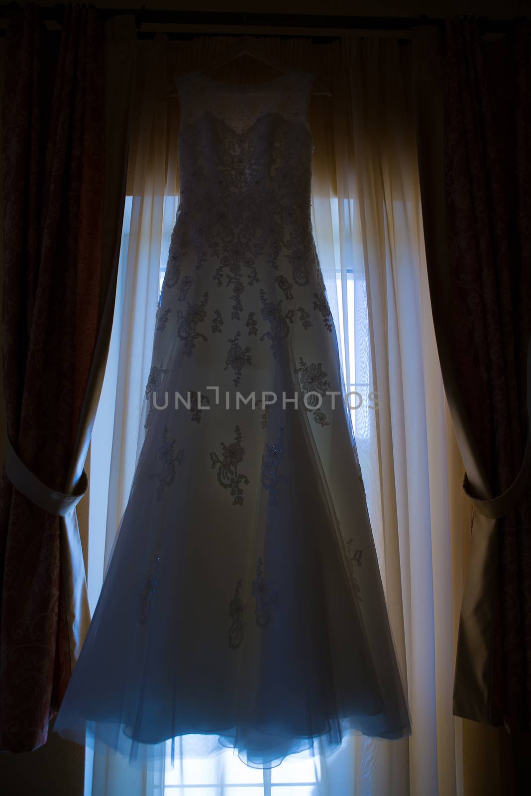 wedding dress hanging on window at hotel room