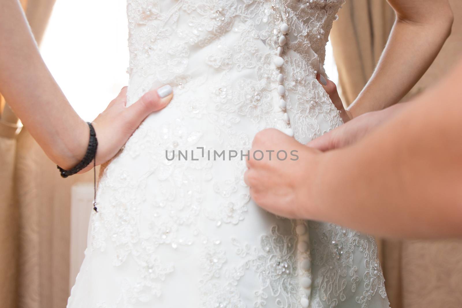 Helping the bride to put her wedding dress on