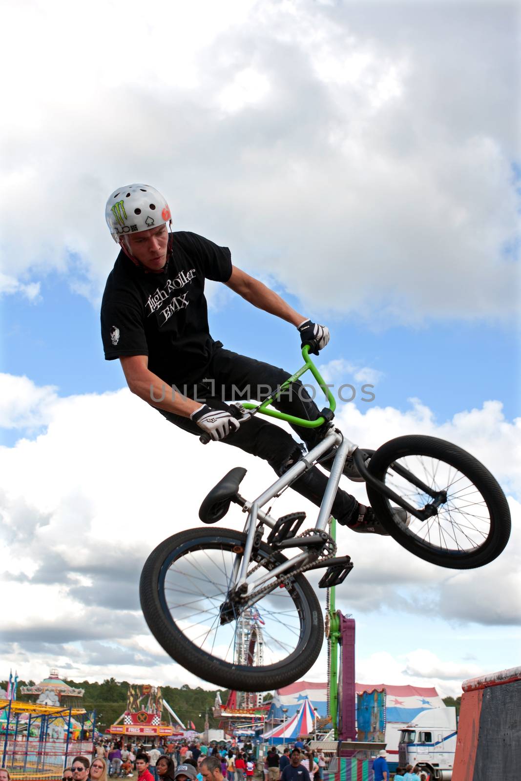 Hampton, GA, USA - September 27, 2014:  A young man with the High Roller BMX club spins his bike in midair while performing a BMX stunt at the Georgia State Fair.
