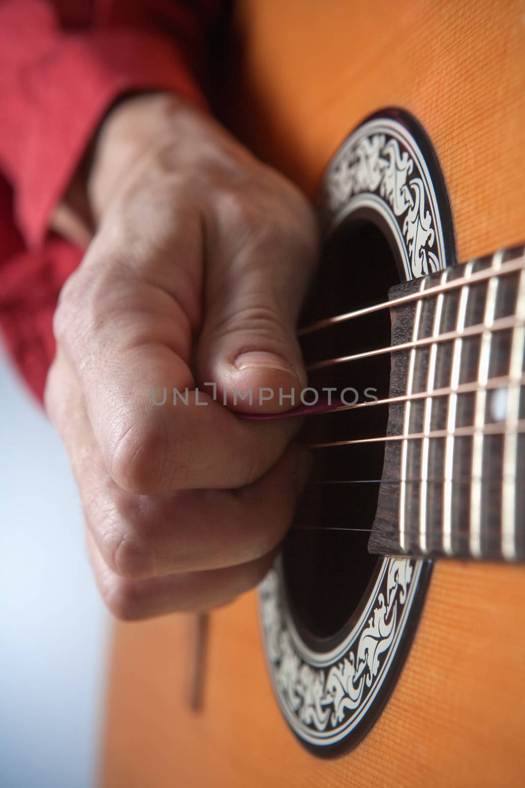 closeup of hands of a musician playing acoustic guitar