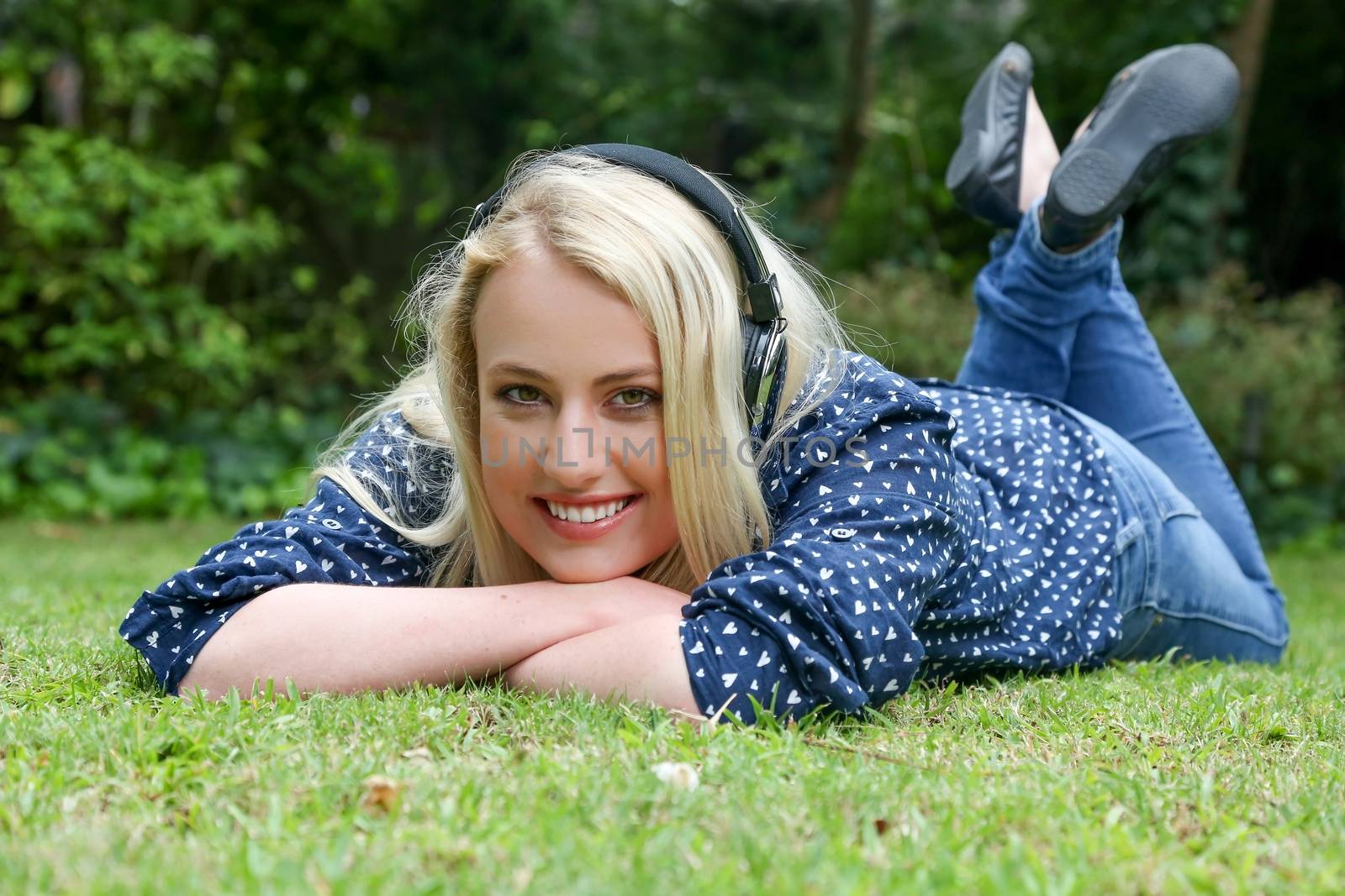Pretty Blond Girl Lying on Grass with Earphones by fouroaks