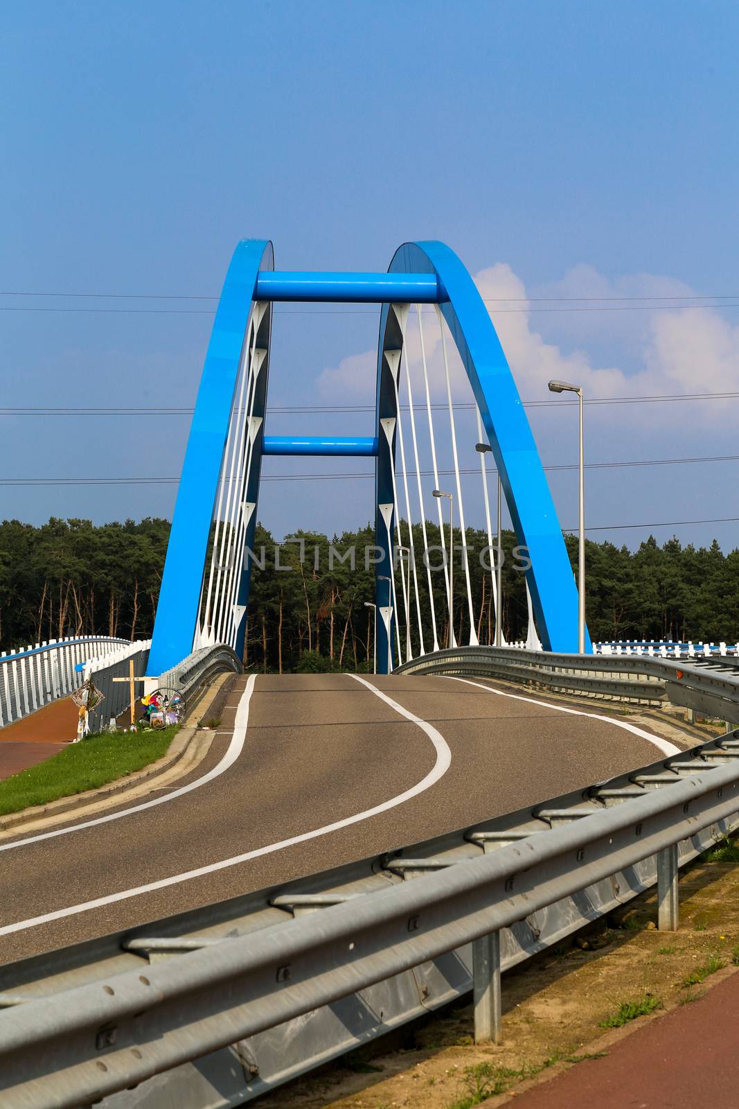 A blue steel structure of a bridge crossing a river