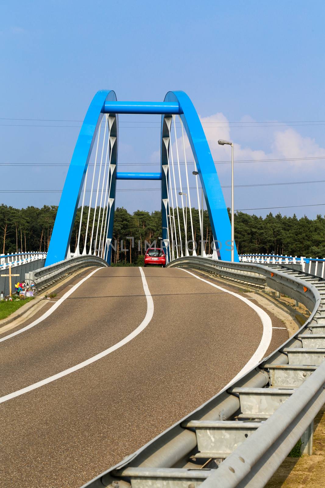 A blue steel structure of a bridge crossing a river