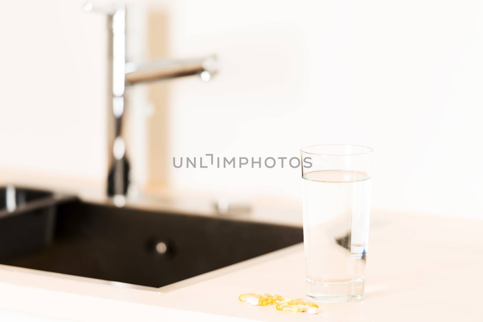 glass of water and pills on kitchen countertop