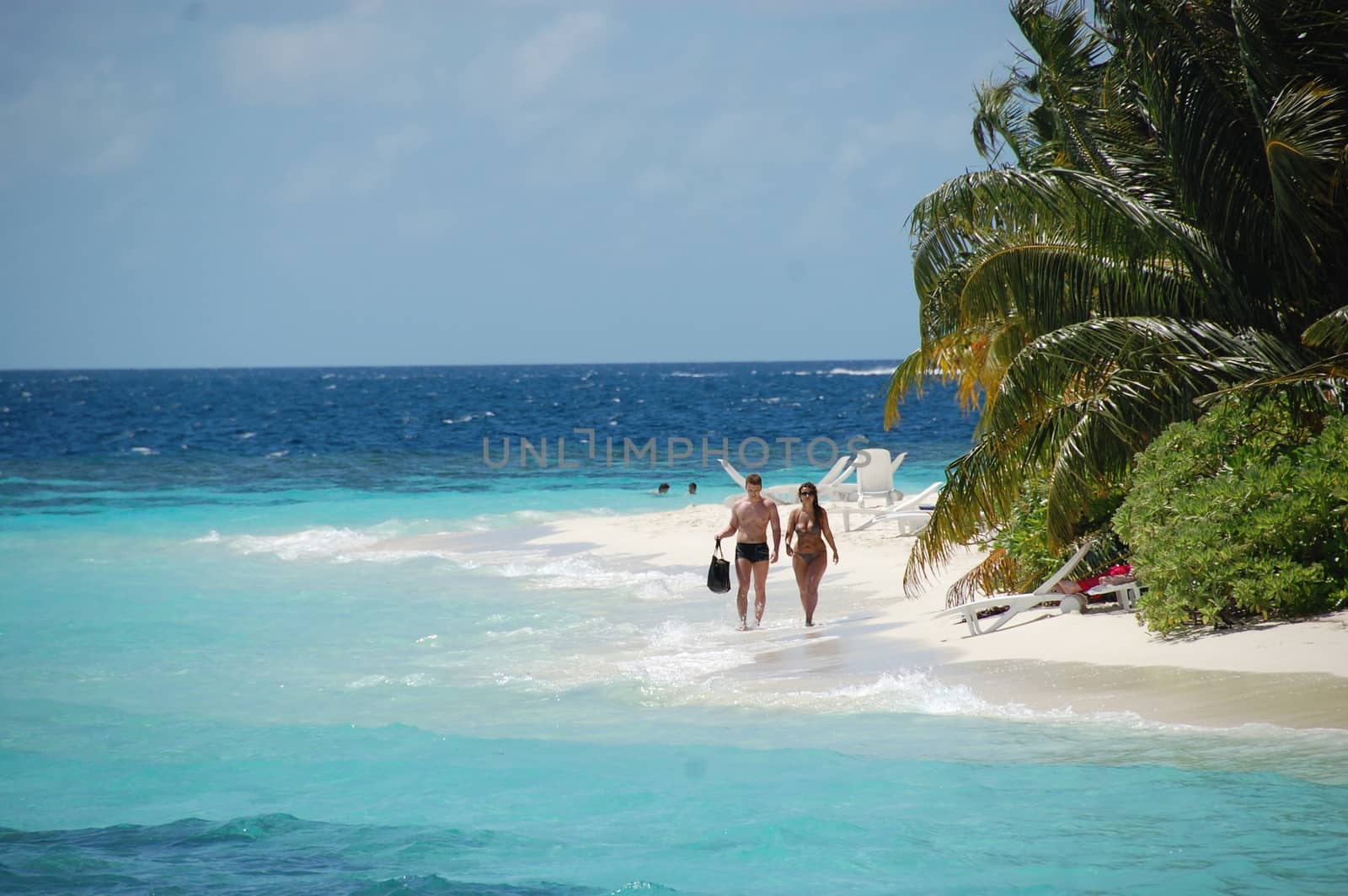 Couple walking at white sand beach Maldives, Bandos island