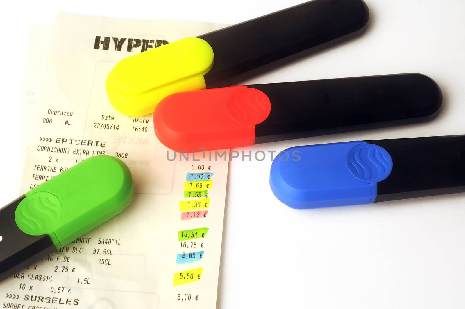 Blue, green, red and yellow highlighters with a receipt from supermarket on white background