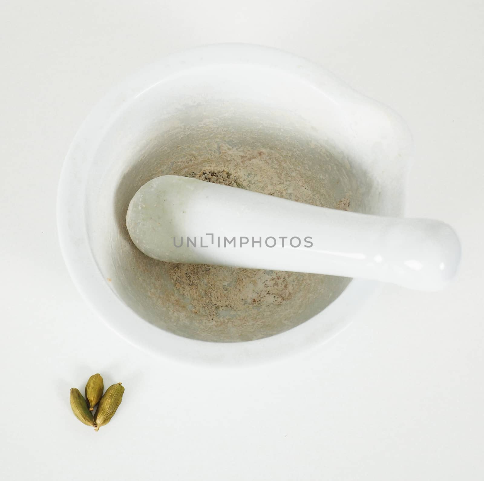 White marble mortar with whole cardamom on the side by Arvebettum