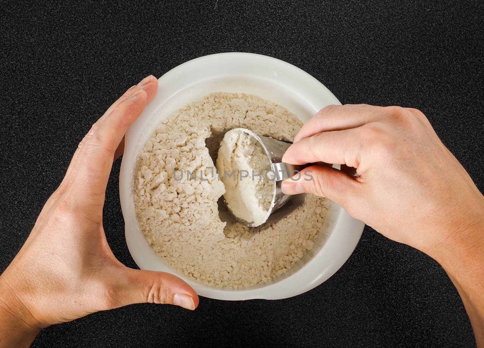 Person using a measurement tool in a bowl of wheat flour by Arvebettum