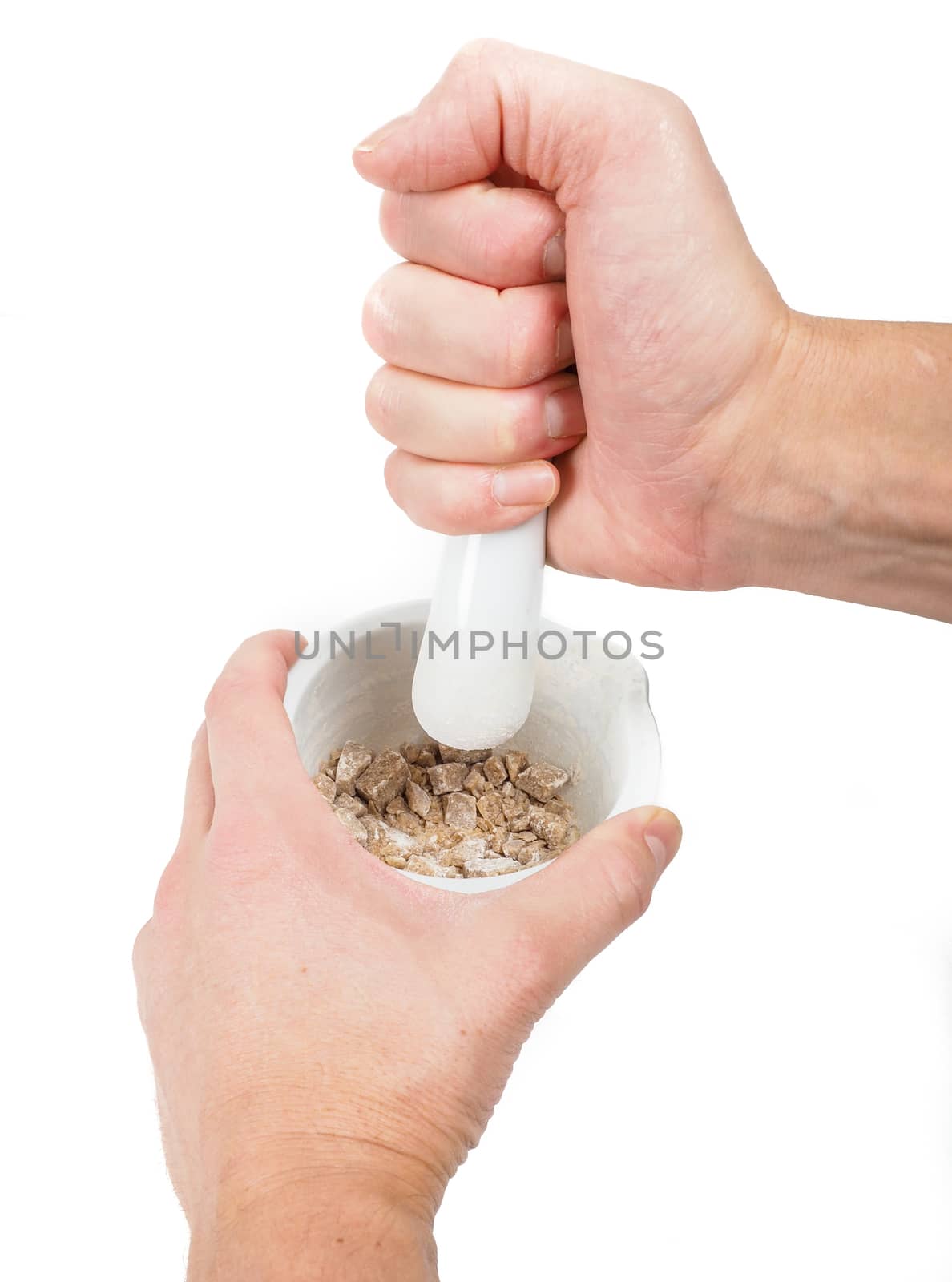 Person crushing brown sugar cubes in a white marble mortar