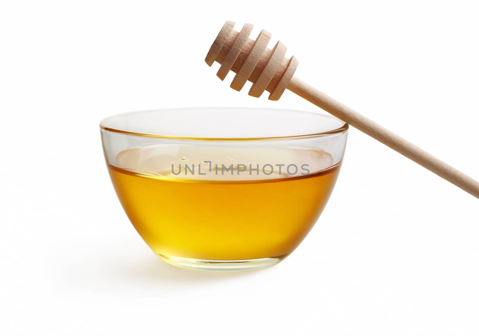 Glass bowl with floral honey and stick isolated on white background.
