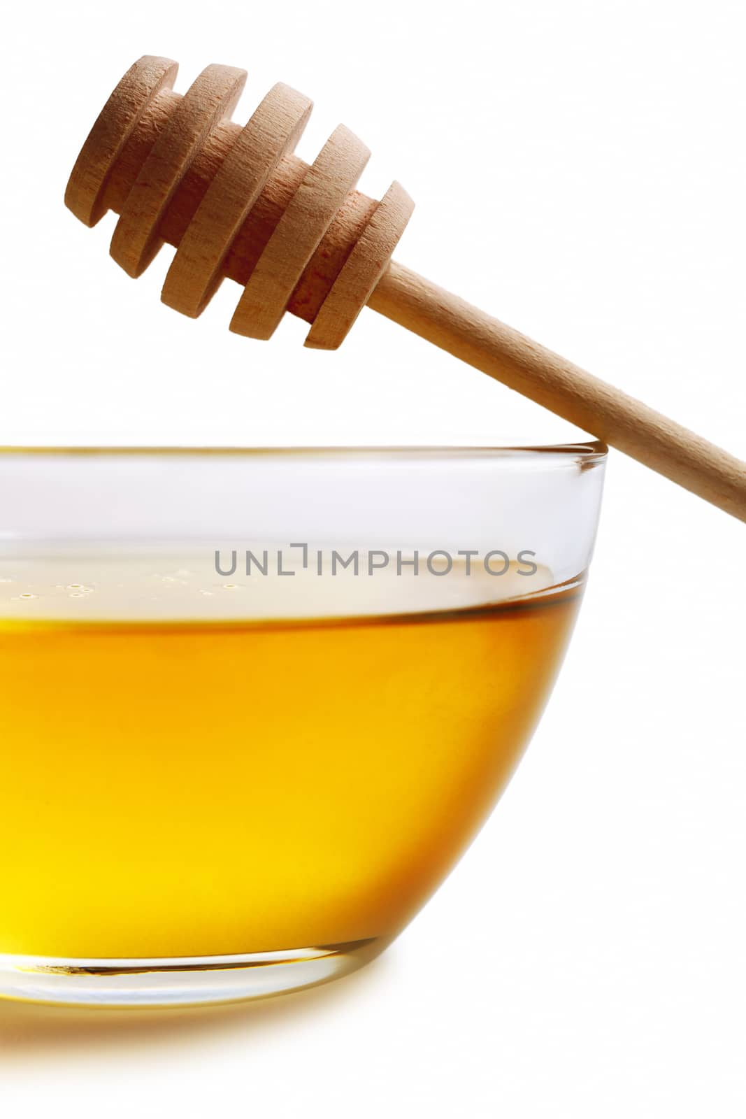 Glass bowl with floral honey and stick isolated on white background.