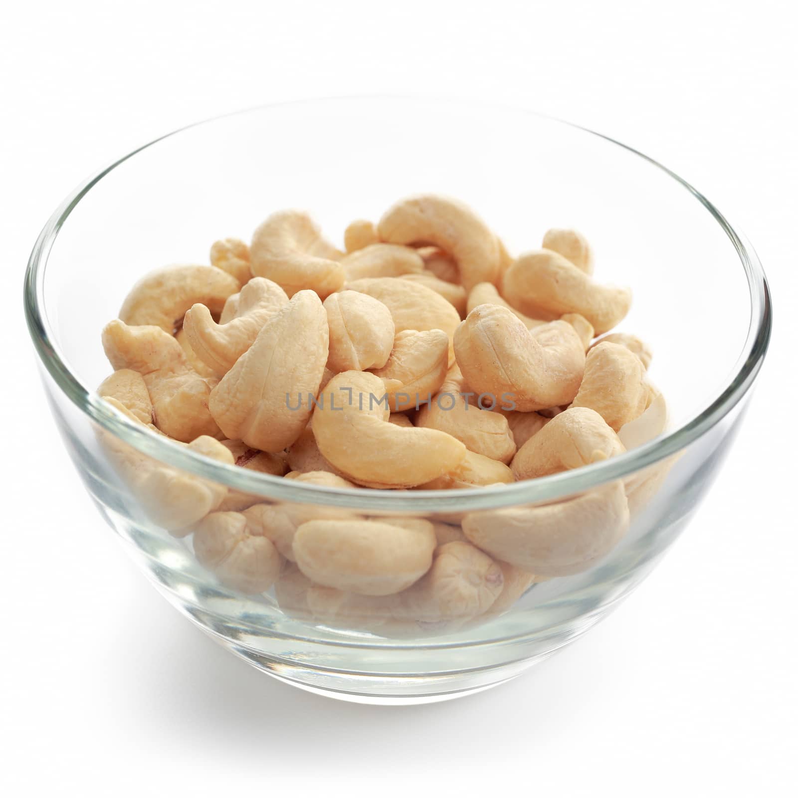 Glass bowl with cashew nuts isolated on white background.