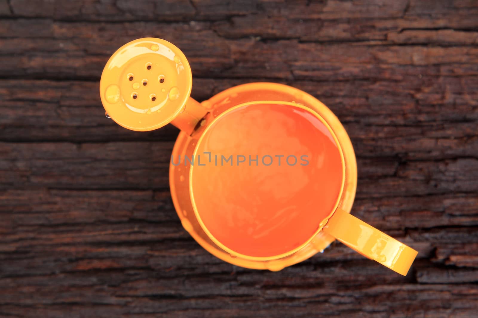 Orange watering can on old wood background