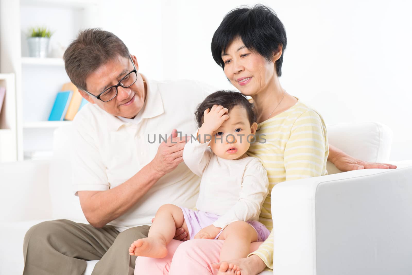 Asian family relaxing at home, grandparents and grandchild living lifestyle indoor.