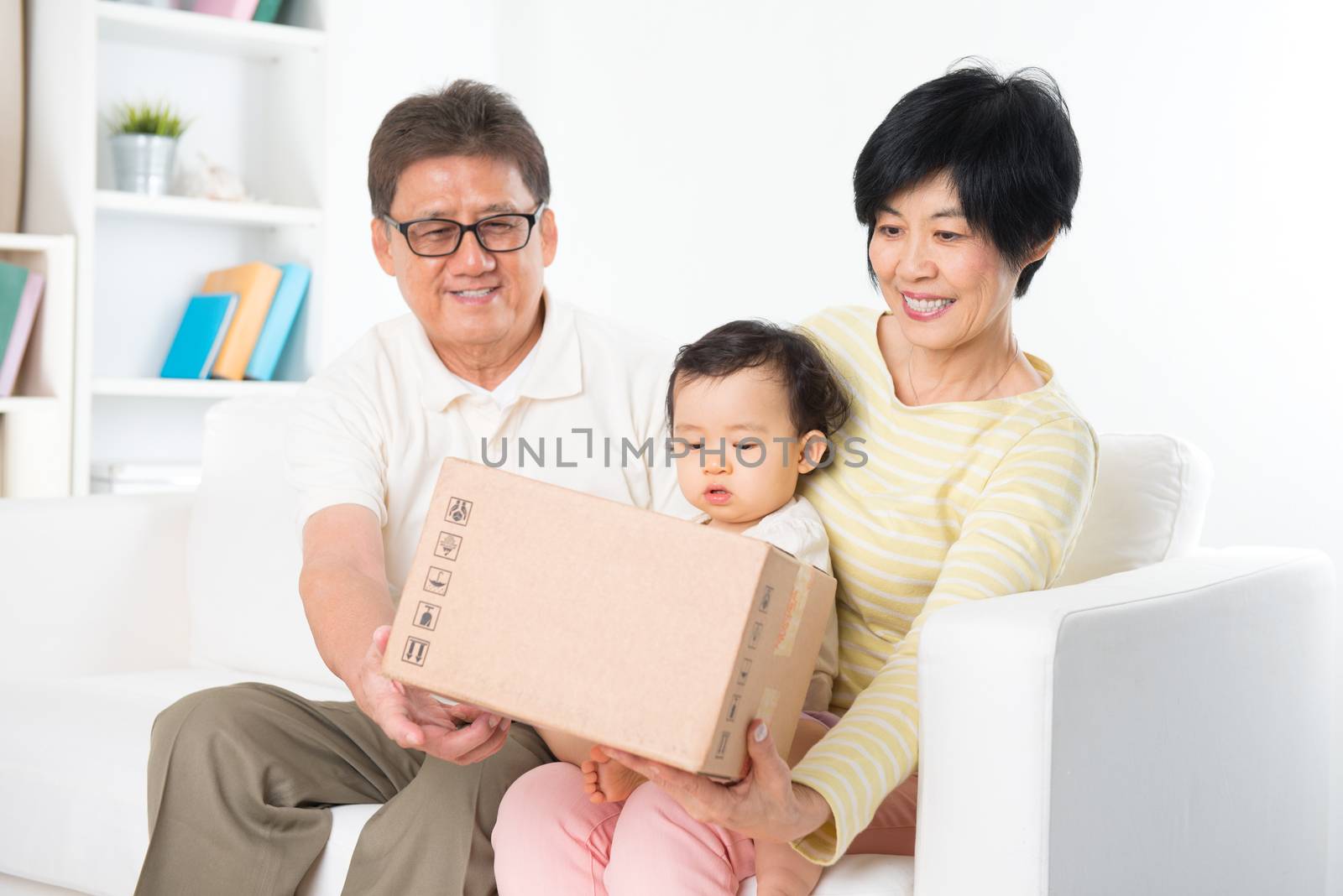 Asian family received an express courier parcel and open it at home, grandparents and grandchild living lifestyle indoor.