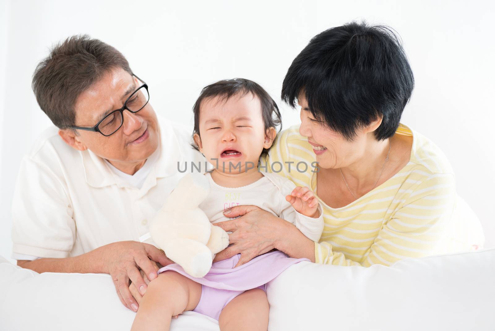 Asian family pamper crying baby girl, grandparents and grandchild indoor living lifestyle at home.