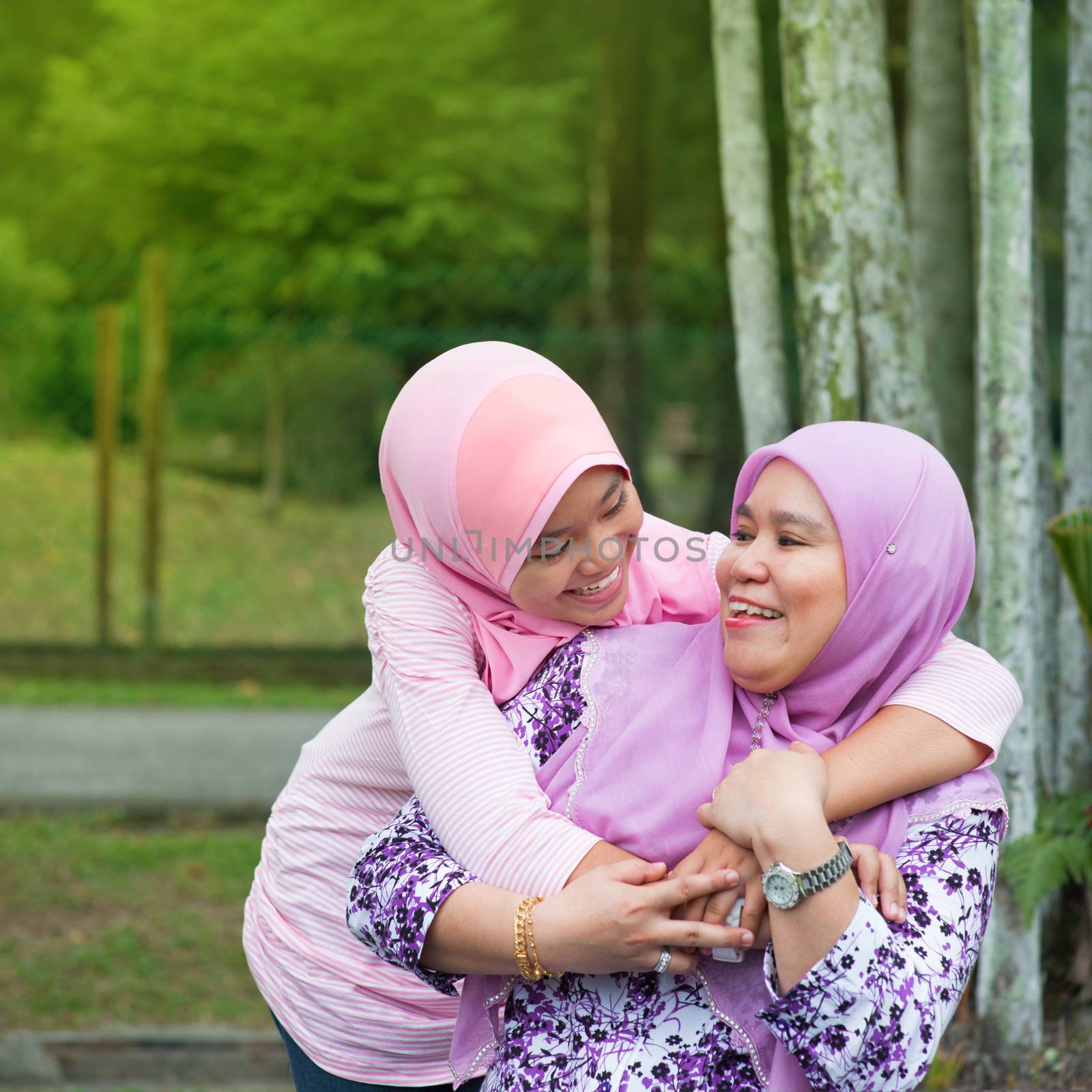 Happy Southeast Asian Muslim mother and daughter at outdoor park, family lifestyle.