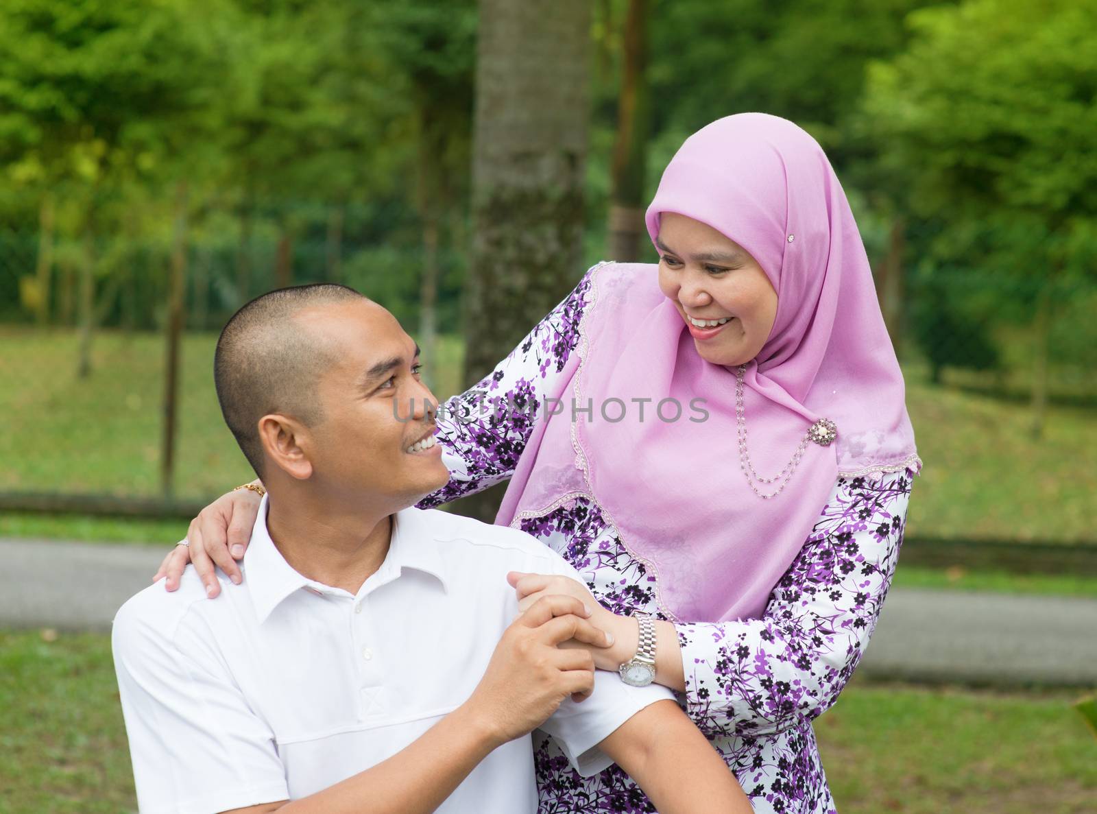 Southeast Asian Muslim couple at outdoor park, happy family lifestyle.